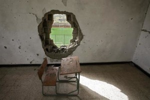 A desk, covered with dirt and debris, sits in a classroom damaged during the conflict, in Libya.